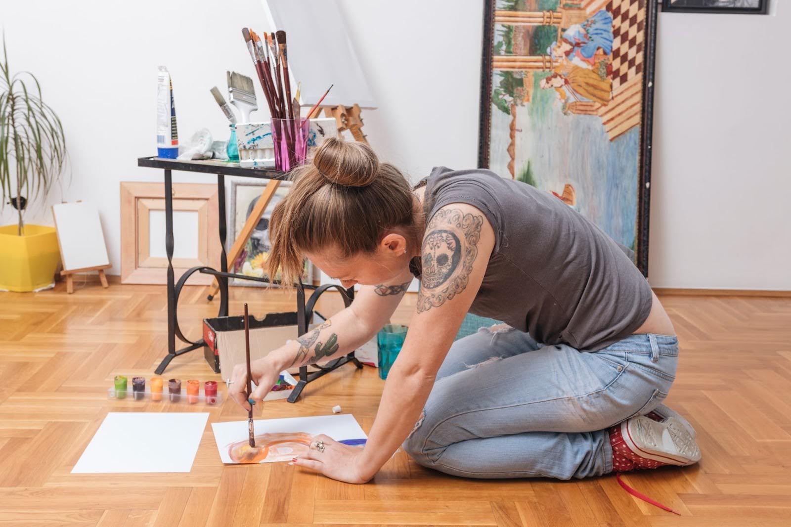 Artist painting on the studio floor using unconventional posture and materials, reflecting studio experimentation and process-driven art.