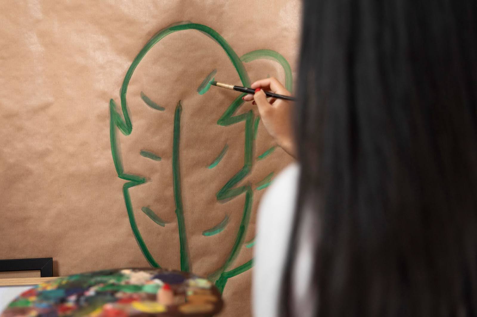 Close-up of an artist painting a leaf motif, representing exploratory art practice and experimentation with natural forms.